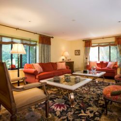 A formal living room with a floral carpet and large windows.