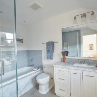 A modern bathroom with a marble vanity top and bathtub front.