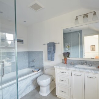 A modern bathroom with a marble vanity top and bathtub front.